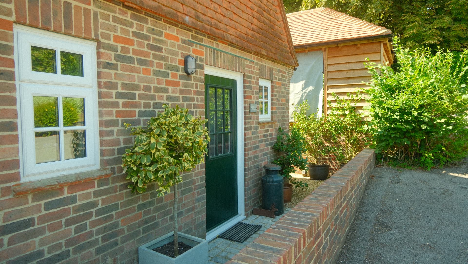 The brick and tile exterior of the cottage with a green front door